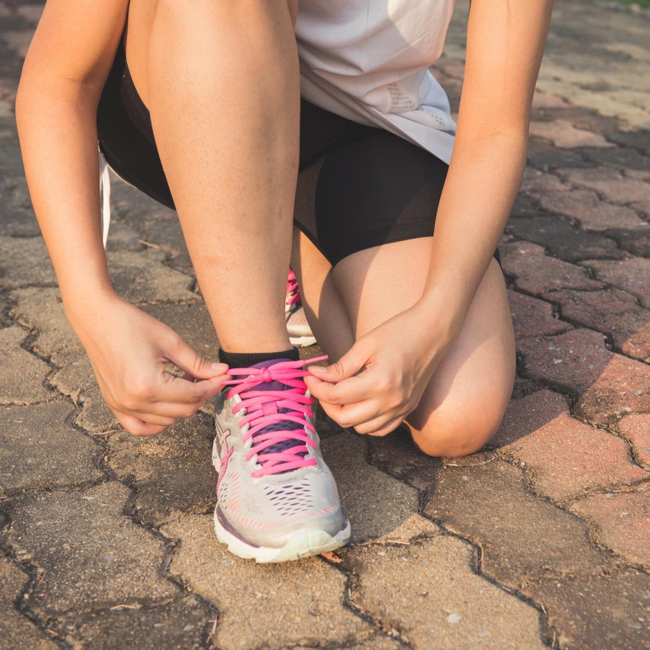 Woman Lacing Up Her Gray and Pink Nike Low-top Athletic Shoe